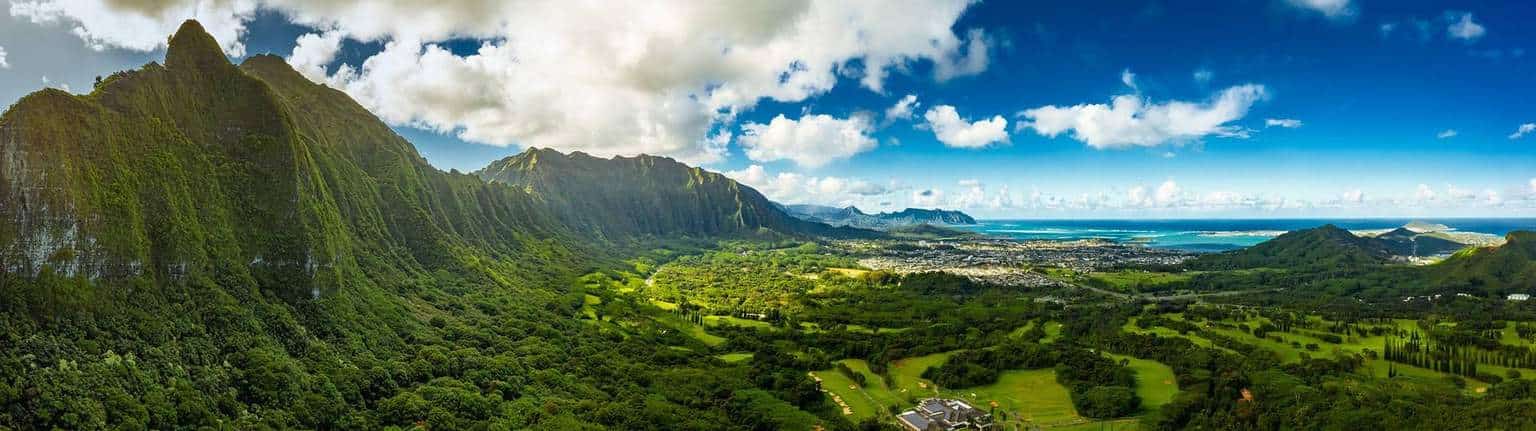 Aerial panorama of Oahu's North Shore mountains, green valley, and coastline