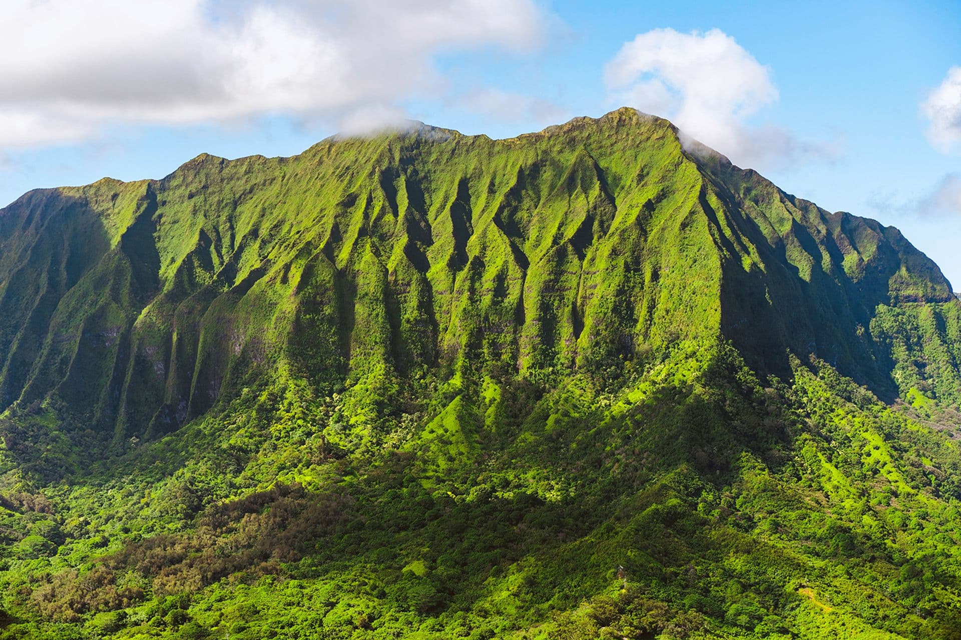 Steep ridgeline of the Ko'olau Mountains on Oahu with clouds at the summit